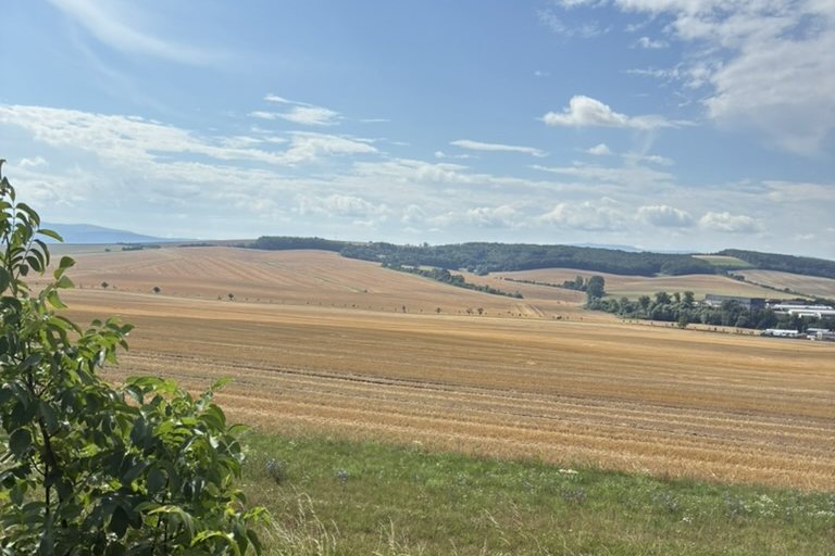 Pozdně letní pole a zvlněná krajina Slovácka pod modrou oblohou