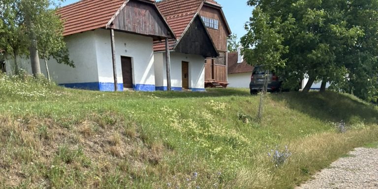Bílé vinné sklepy s modrou podezídkou a dřevěnými štíty